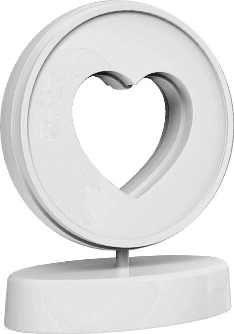 Smiling woman taking a selfie in front of a painted heart sculpture.